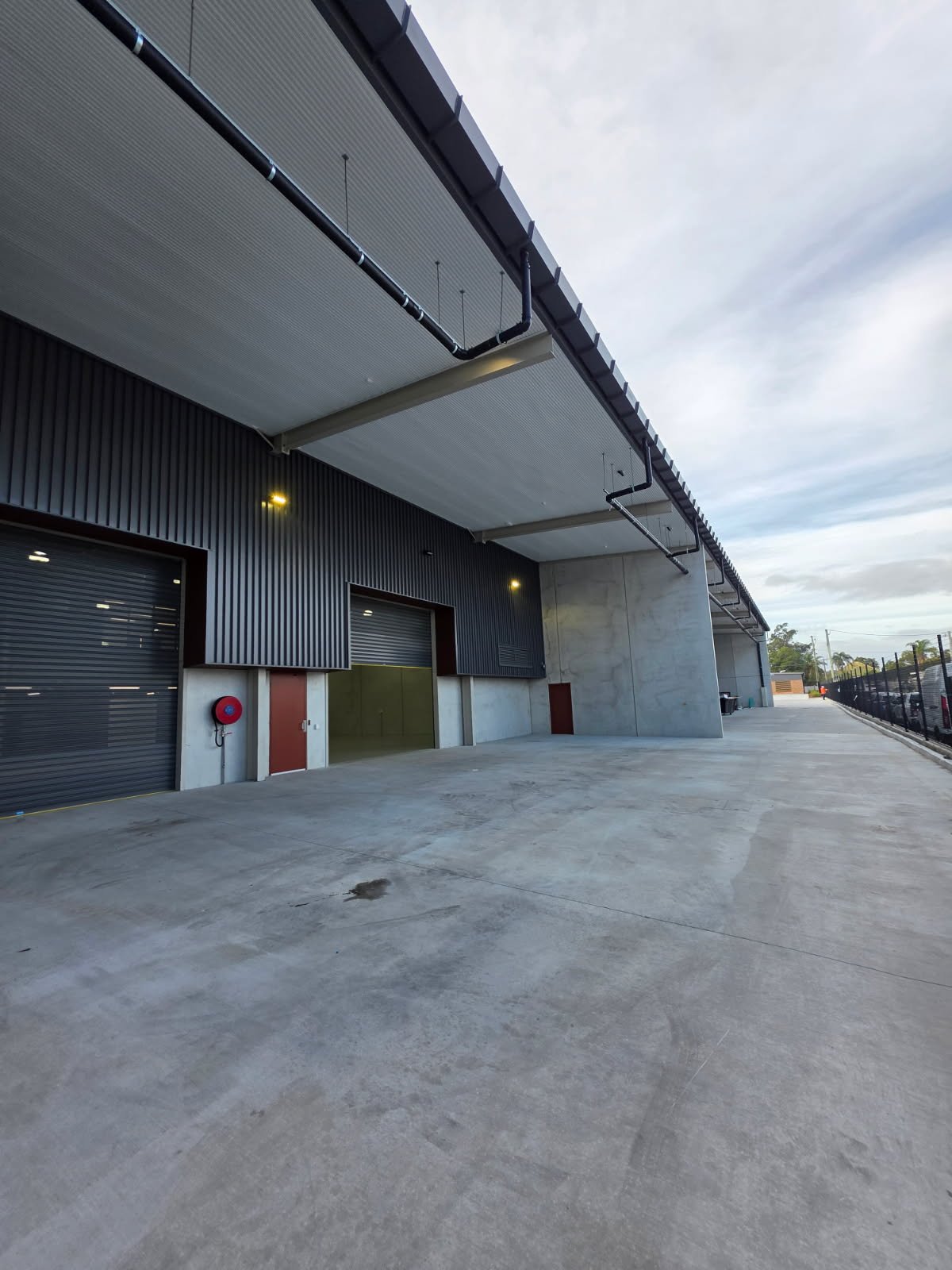 Industrial building exterior with wall-mounted fire hose reel serviced by Safe QLD