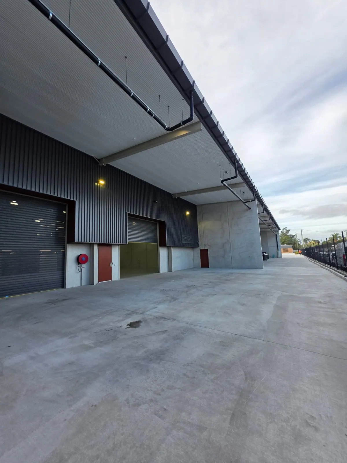 Industrial building exterior with wall-mounted fire hose reel serviced by Safe QLD