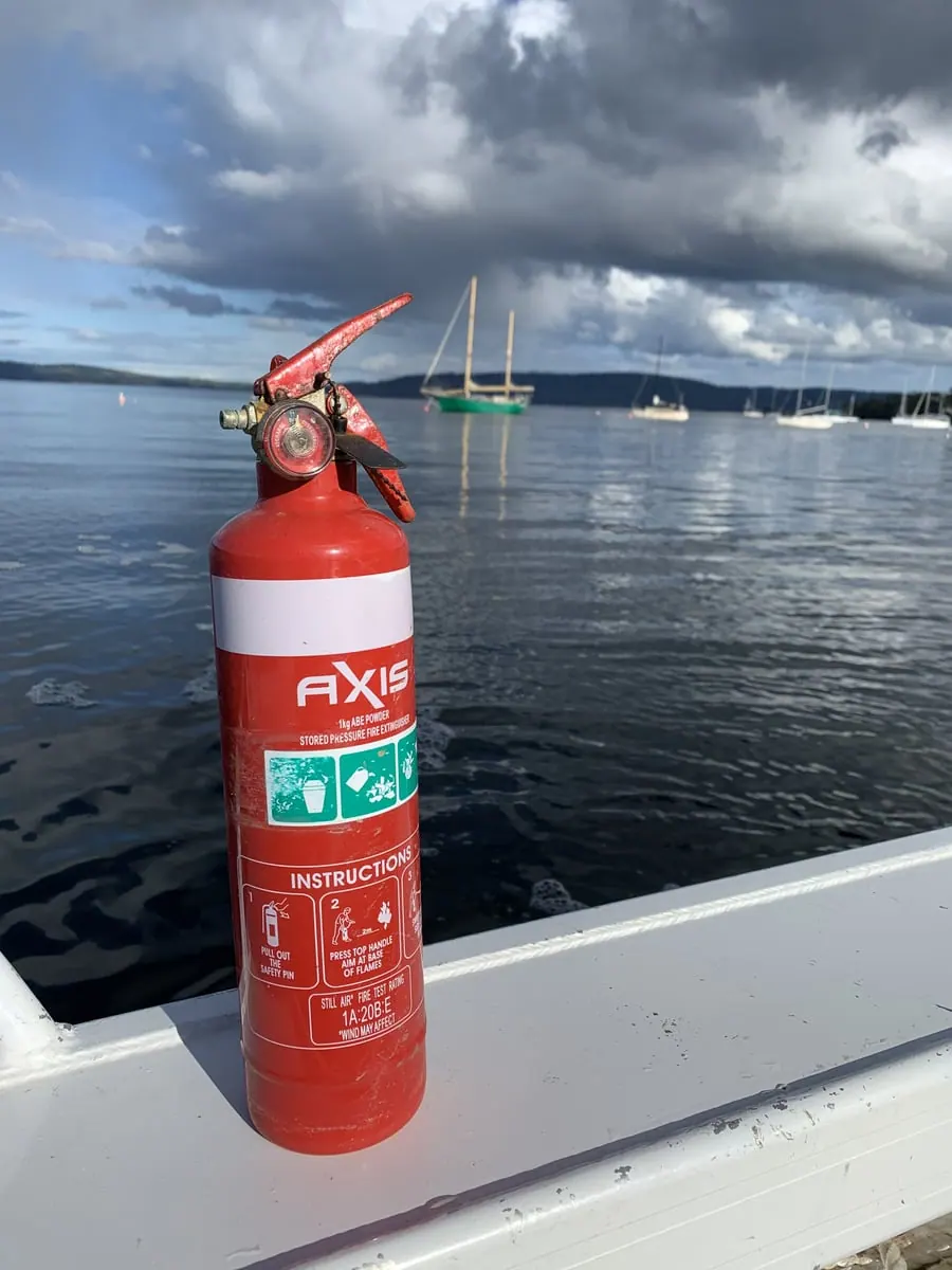 Fire extinguisher mounted on a vessel with the marina behind, serviced by Safe QLD