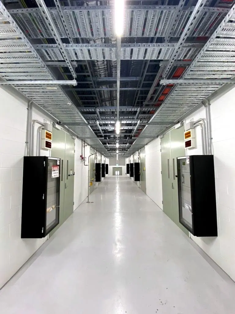 Services corridor with overhead cable trays in a temperature-controlled facility