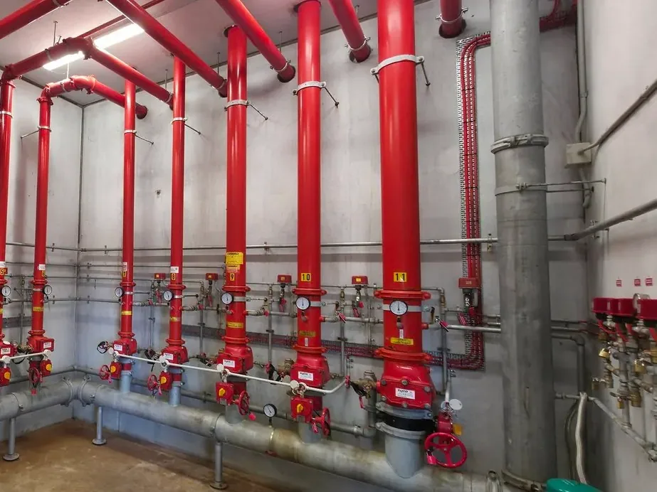 Numbered sprinkler risers, alarm valves and pressure gauges in a high-rise sprinkler valve room maintained by Safe QLD Fire Protection