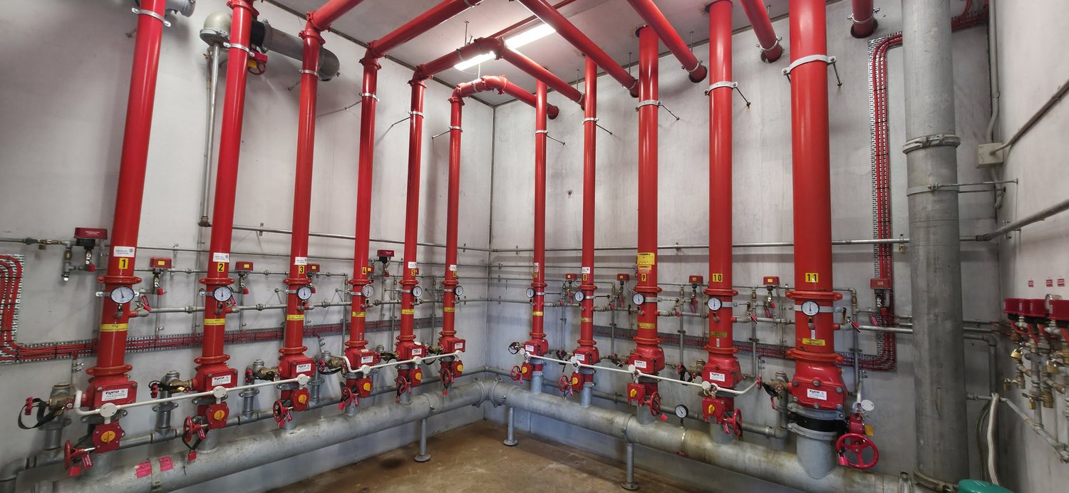 Red sprinkler and fire pump room pipework with numbered valves serviced by Safe QLD