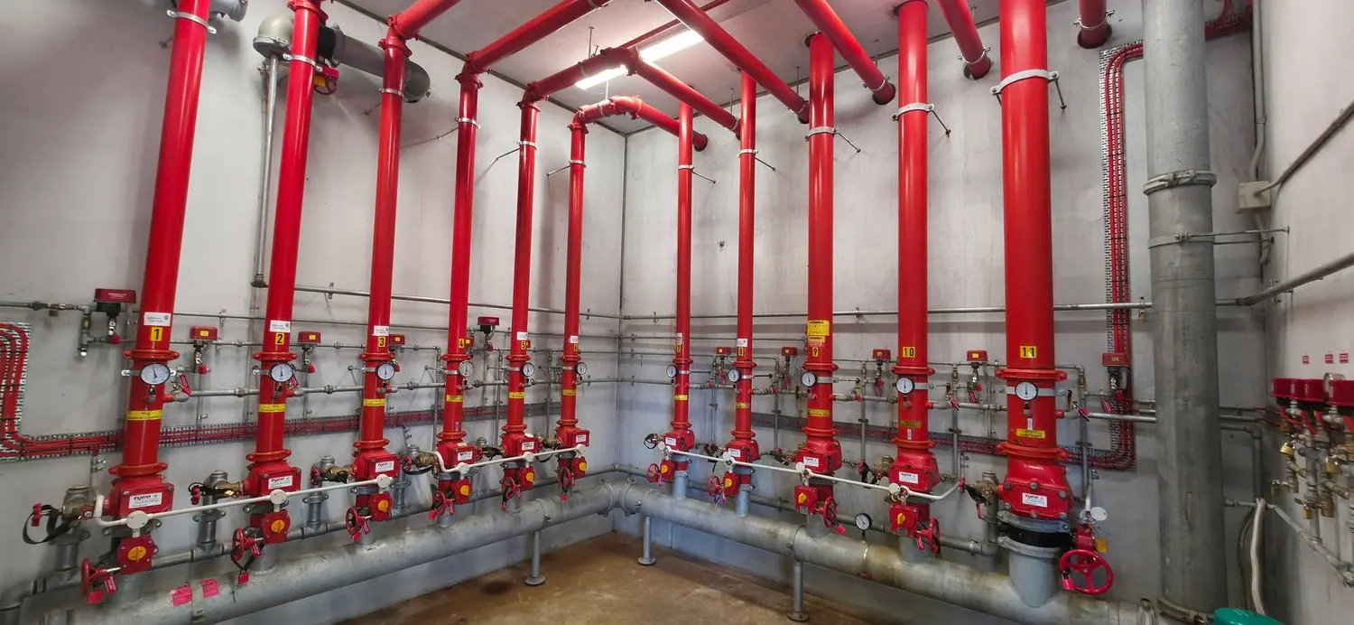 Red sprinkler and fire pump room pipework with numbered valves serviced by Safe QLD